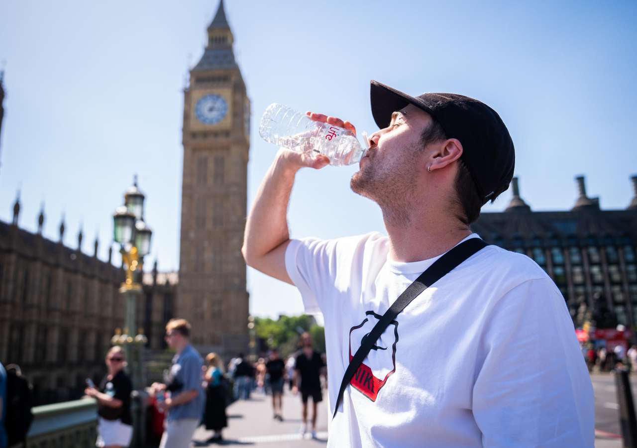 A person cools down with a bottle of water during the hot weather on Westminster Bridge in London on Monday. (AP-Yonhap)