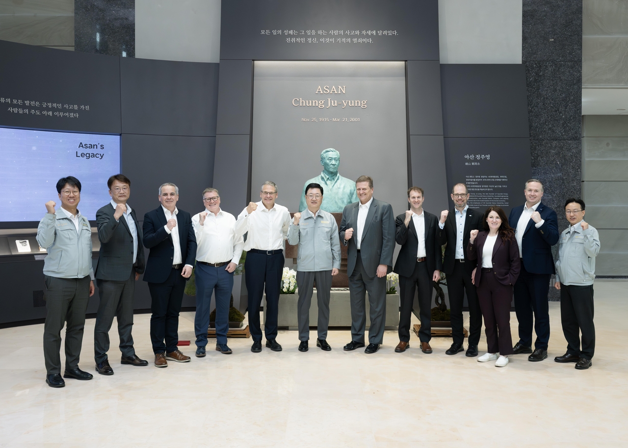 Dirk Lesko (sixth from right), president of Irving Shipbuilding; Joo Won-ho (sixth from left), president of HD Hyundai Heavy Industries and head of its naval and medium-sized ship business; and Irving Shipbuilding senior executives pose for a photo in front of a bust of HD Hyundai founder Chung Ju-yung during a visit to HD Hyundai Heavy Industries’ Ulsan headquarters in early May. (HD Hyundai Heavy Industries)