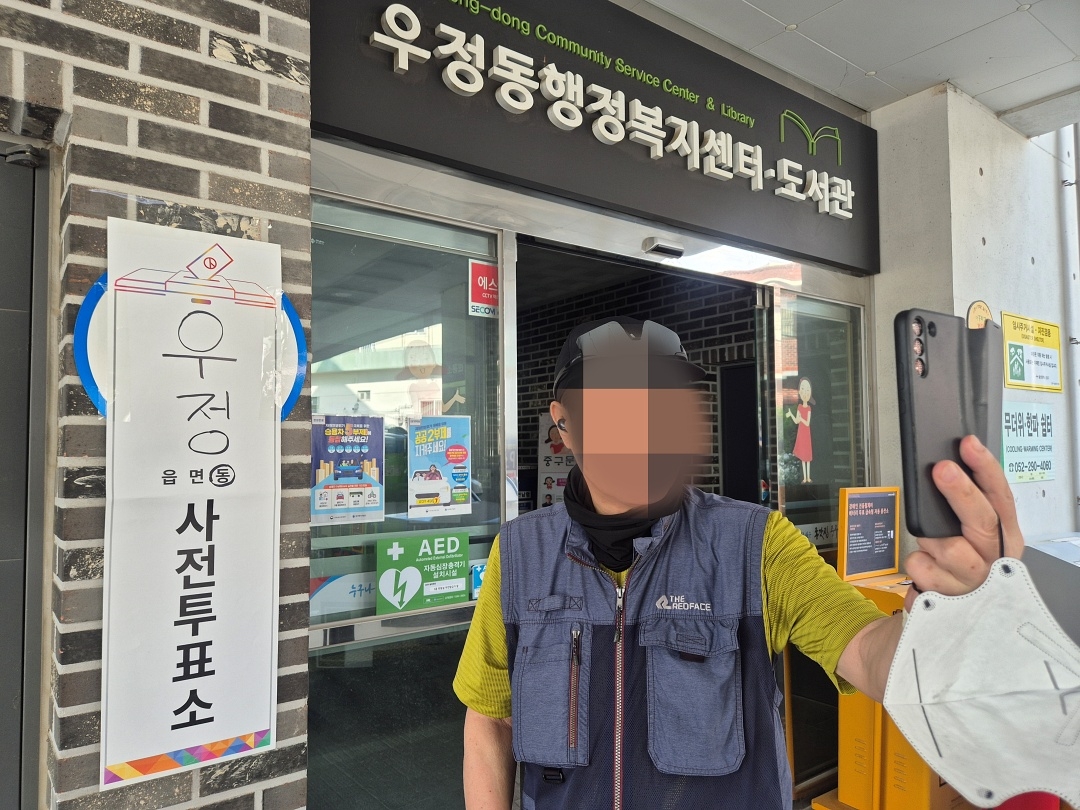 A voter takes a selfie beside a polling station sign in Ulsan on Friday. (Newsis)