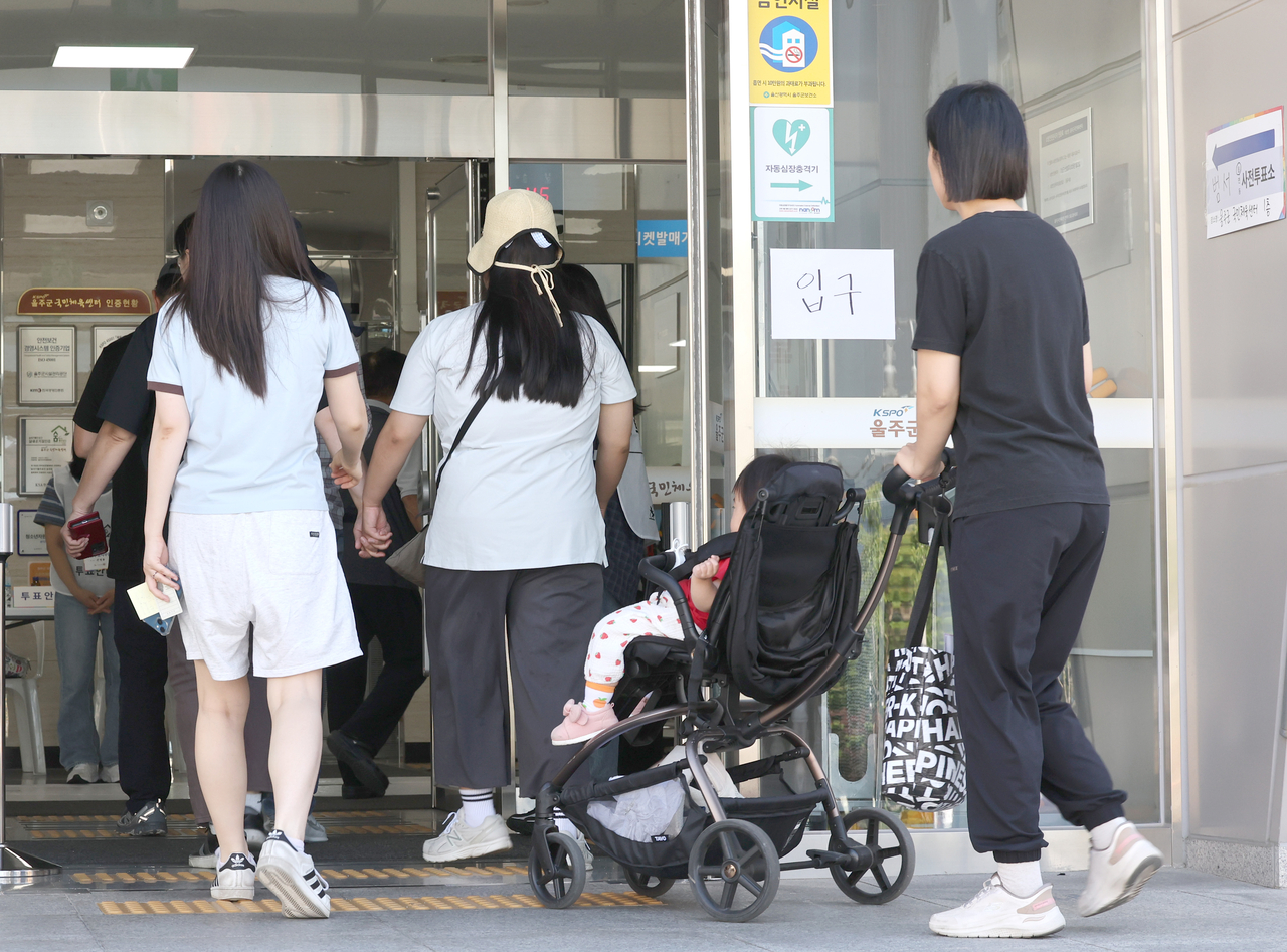 A parent arrives with a child at an early voting station in Ulsan on Saturday. Parents accompanied by their children were a common sight at polling stations during the two-day early voting period. (Yonhap)