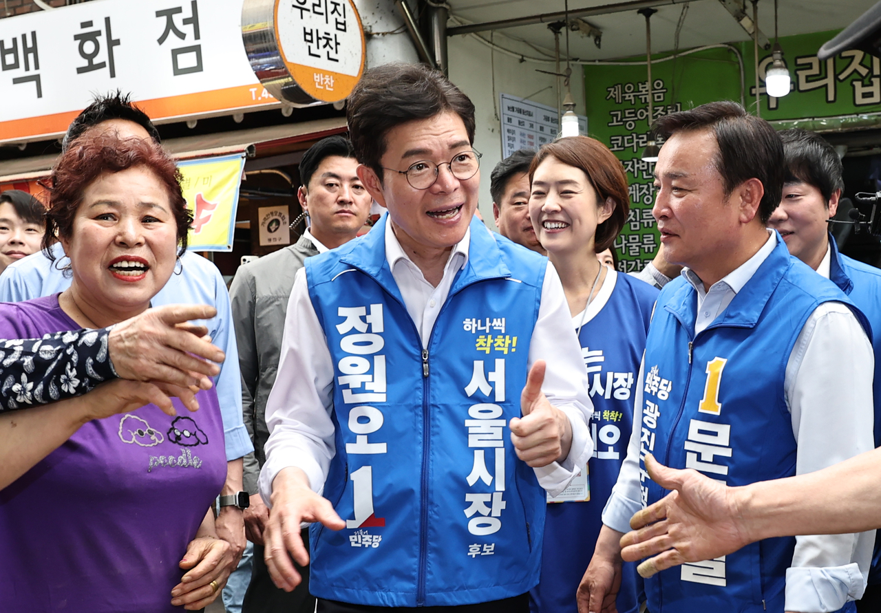 Democratic Party Seoul mayoral candidate Jung Won-oh speaks with merchants during a visit to Jayang Traditional Market in Seoul's Gwangjin-gu on Saturday. (Yonhap)