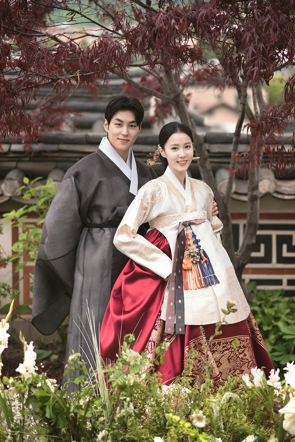 A couple wearing hanbok poses for a photo, with the woman dressed in a traditional "geodeul chima" (Leesungmin Hanbok)
