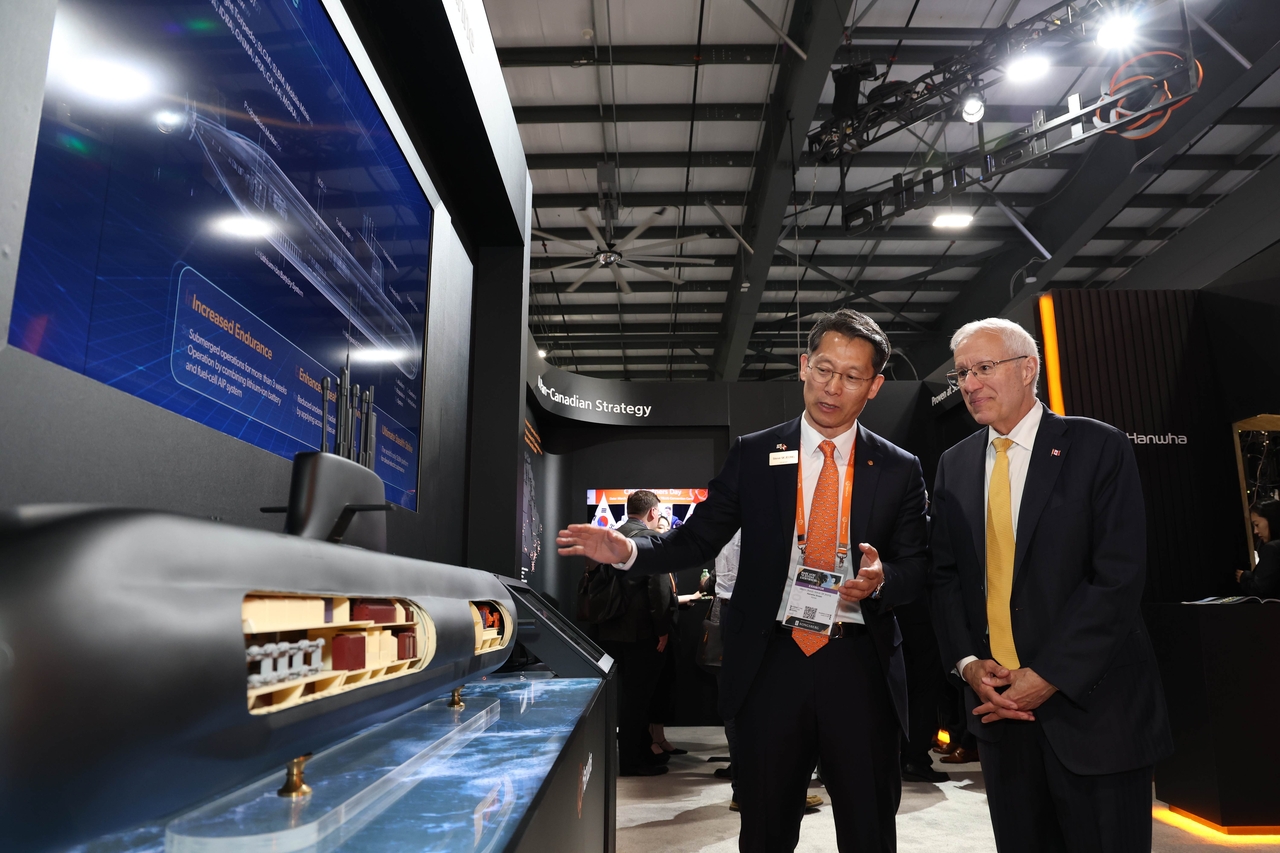 Steve SK Jeong(left), senior executive vice president and Head of Naval Ship International Business at Hanwha Ocean, speaks with Victor Fedeli, Ontario’s Minister of Economic Development, Job Creation and Trade, at the company’s exhibition booth during CANSEC 2026 in Ottawa, Canada, on Thursday. (Hanwha Ocean)