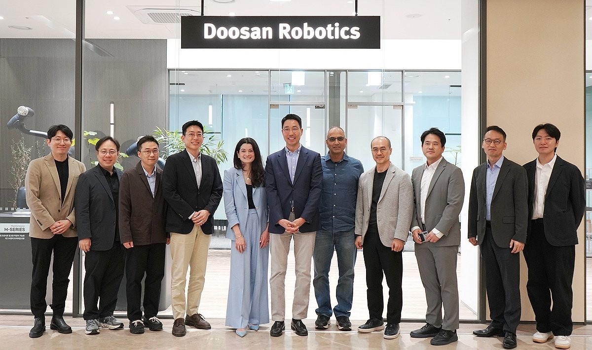 Doosan Robotics chief executive Kim Min-pyo (center) and Madison Huang (fifth from left), an Nvidia senior director and daughter of CEO Jensen Huang, pose with officials at the firm's innovation center in Bundang, Gyeonggi Province, on April 29, when the companies launched a partnership on AI-driven robots. (Doosan Robotics)