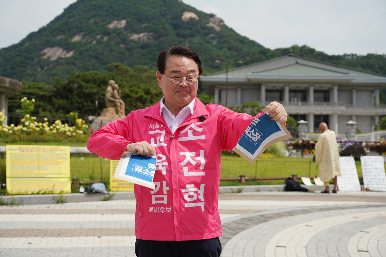 Conservative Seoul Metropolitan Education Superintedent candidate Cho Chun-hyuk rips apart a paper marked "Notice of Withdrawal of Prosecution" in front of Cheongwadae, on Monday, pledging to teach students "why it is wrong for the prosecution to drop charges against President Lee Jae Myung." (Cho Chun-hyuk's campaign office)