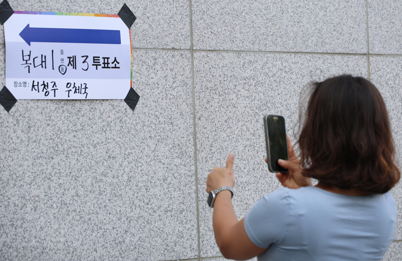 A voter poses for a photo outside a polling station set up at Seo Cheongju Post Office in Cheongju, North Chungcheong Province, Wednesday. (Yonhap)