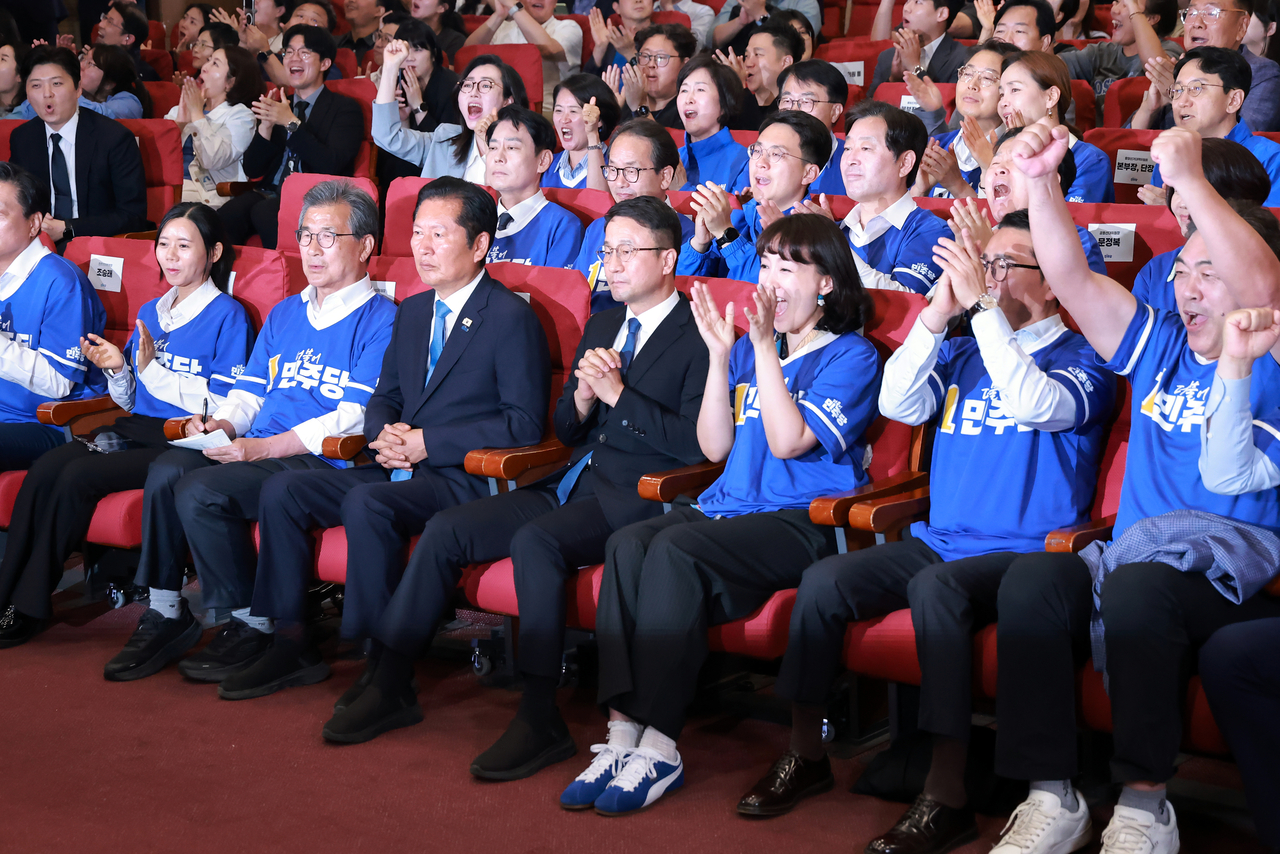 Democratic Party members, including chair Rep. Jung Chung-rae (third from left, front row) and floor leader Rep. Han Byung-do (fourth from left, front row) cheer as the exit poll results for the election are broadcast at the National Assembly on Wednesday. (Im Se-jun/The Korea Herald)