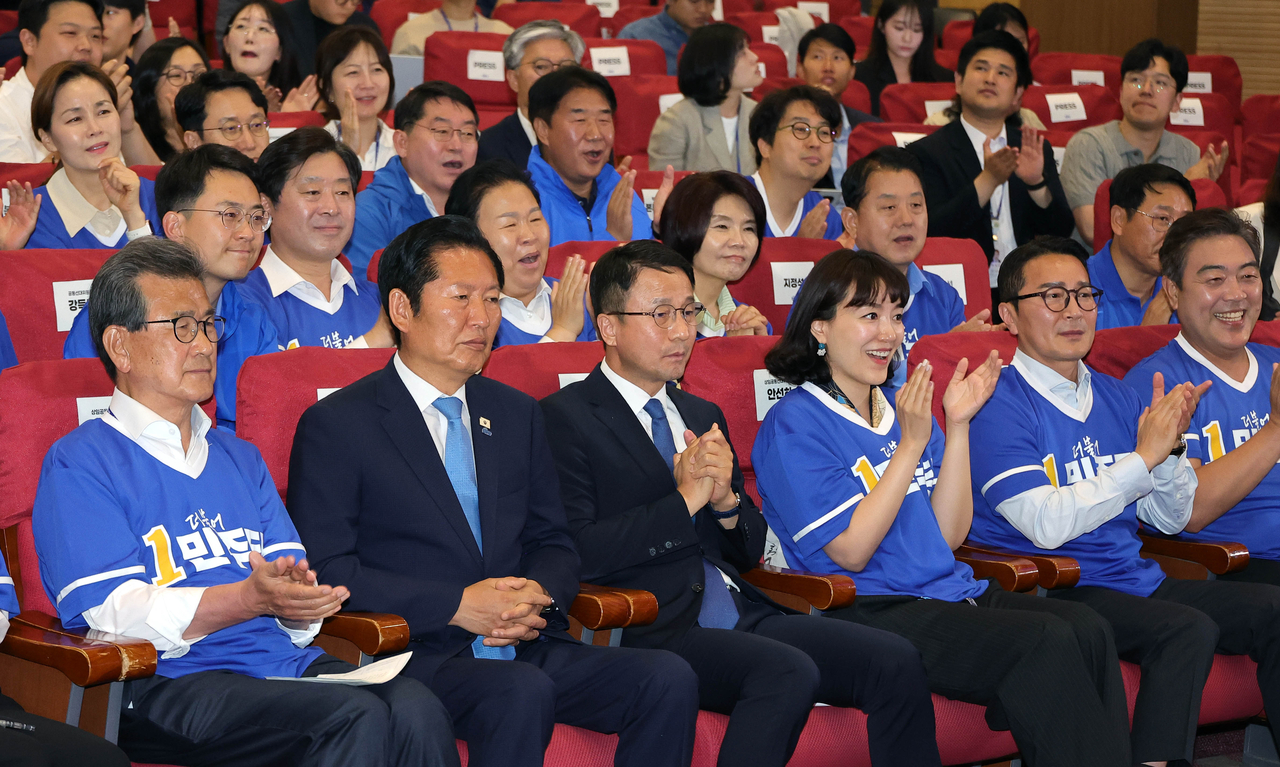 Democratic Party members, including chair Rep. Jung Chung-rae (second from left, front row) and floor leader Rep. Han Byung-do (third from left, front row) cheer as the exit poll results for the election are broadcast at the National Assembly on Wednesday. (Im Se-jun/The Korea Herald)