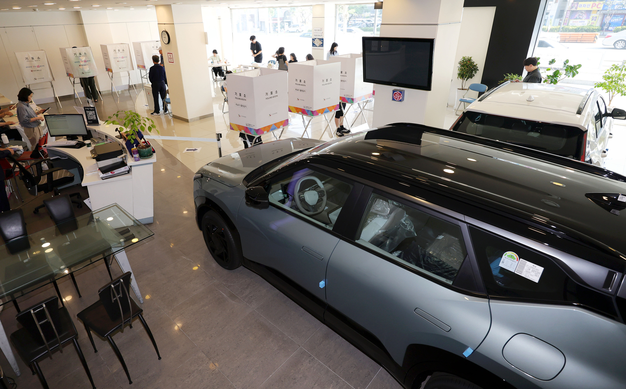 People cast their ballots at a Kia sales outlet serving as a polling station in Seoul on Wednesday. (Newsis)