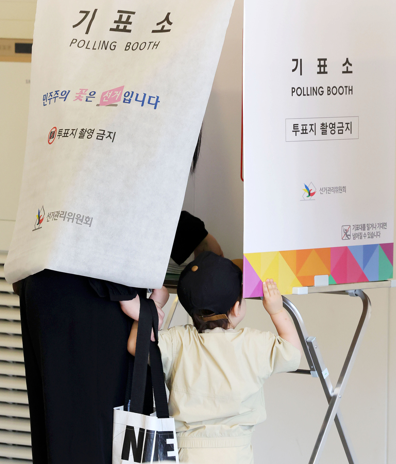 A child peeks inside a booth at a polling station in Seoul on Wednesday. (Newsis)