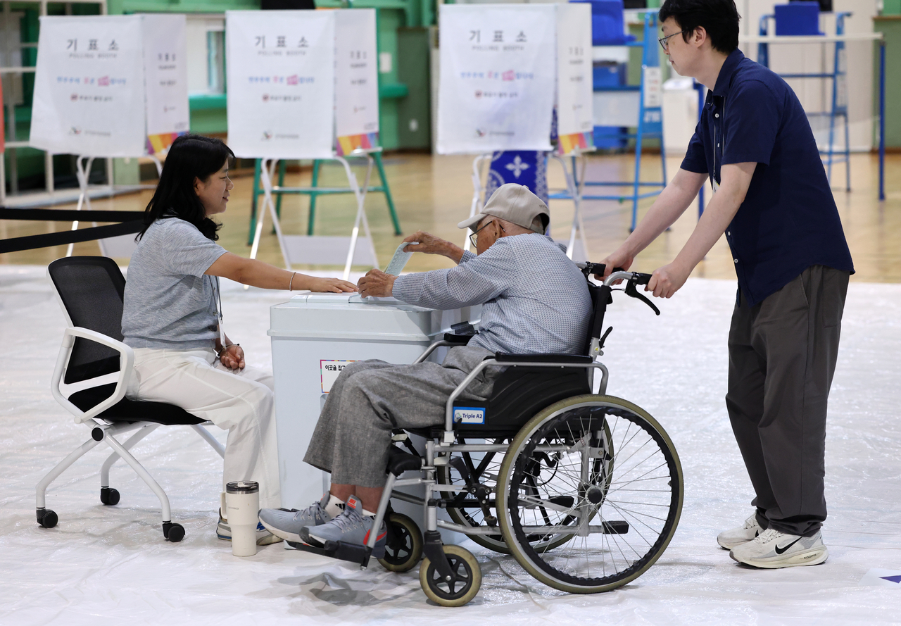 An elderly voter in a wheelchair casts a ballot at a polling station in Seoul on Wednesday. (Yonhap)