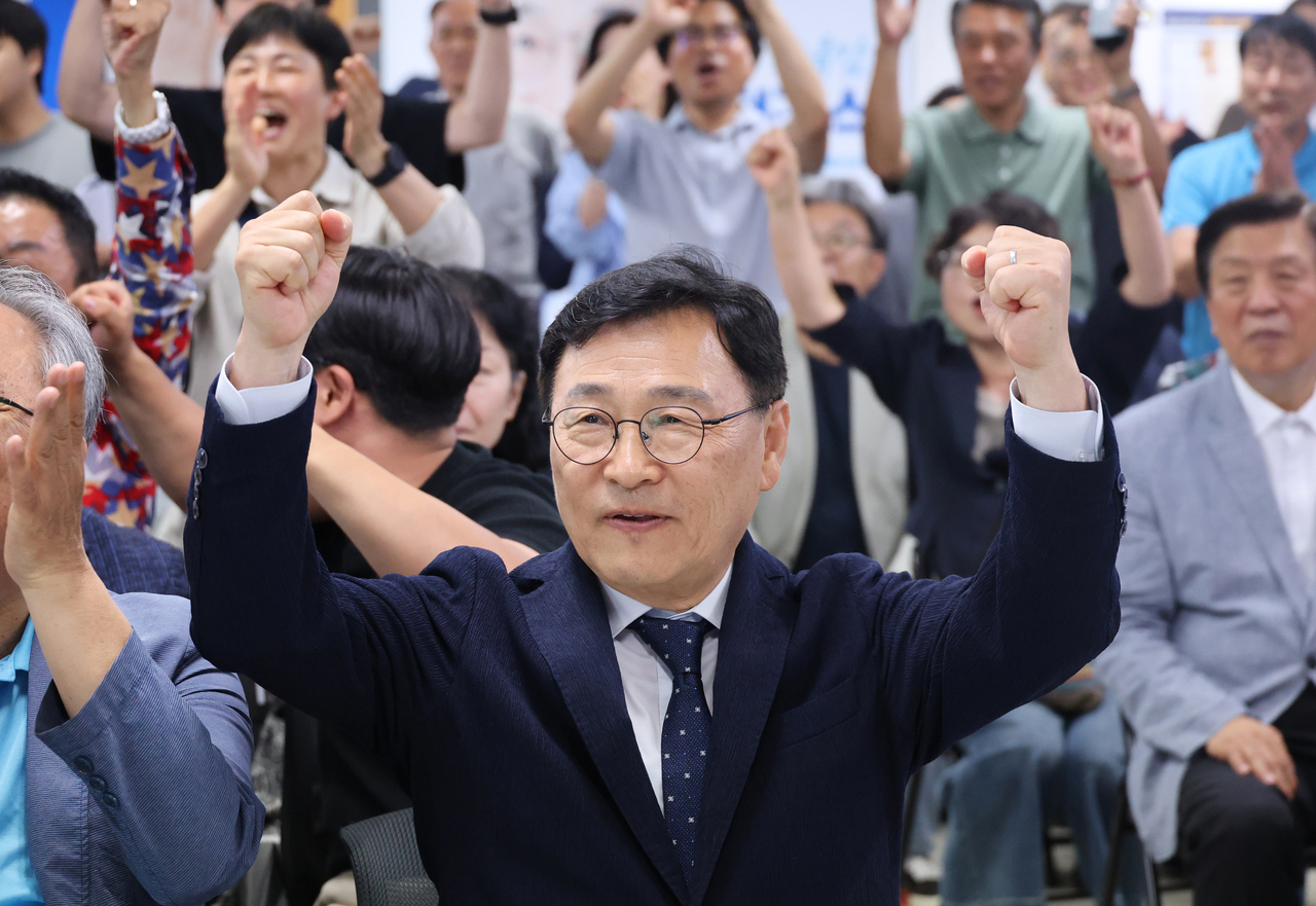Liberal Seoul Metropolitan Education Superintendent candidate Jung Geun-sik (center) puts up two fists on Wednesday at his campaign office as exit polls showed he was projected to win a second term. (Yonhap)