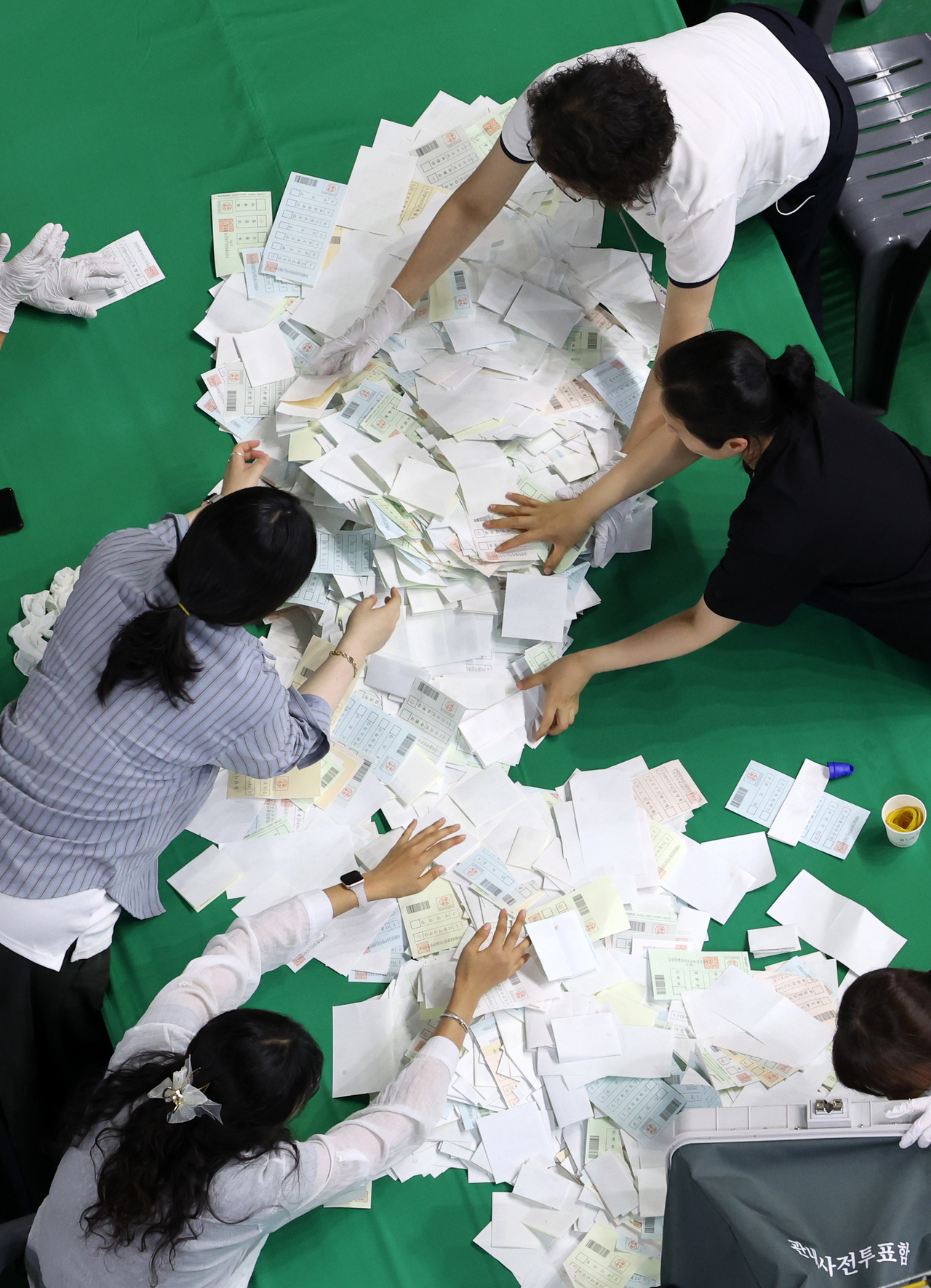 A close-up photo shows election workers sorting ballot papers at a counting center set up inside Hoban Gymnasium in Chuncheon, Gangwon Province, Wednesday. (Yonhap)