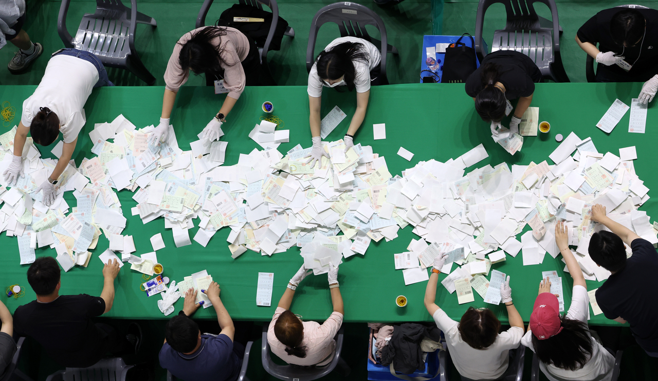 A close-up photo shows election workers sorting ballot papers at a counting center set up inside Hoban Gymnasium in Chuncheon, Gangwon Province, Wednesday. (Yonhap)