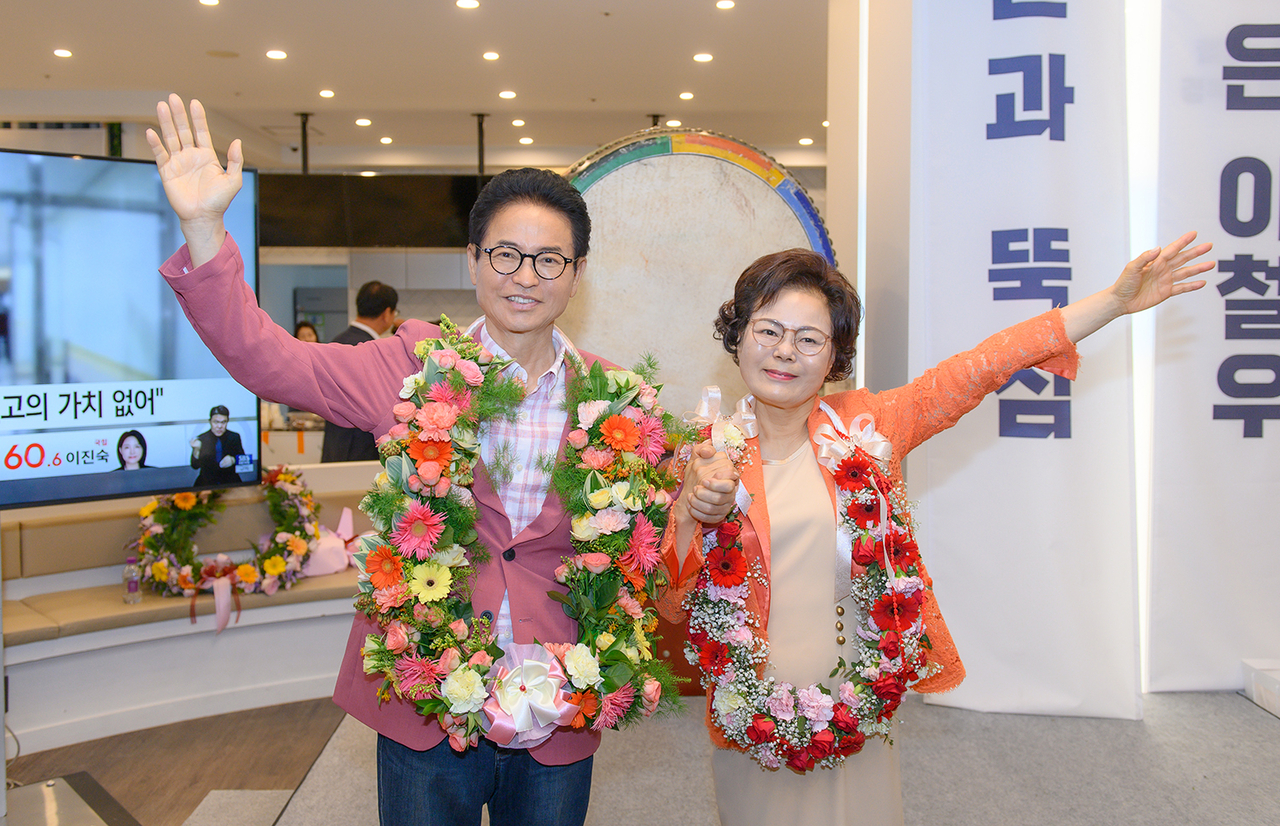 Lee Cheol-woo, who won a third term as North Gyeongsang Province governor in the June 3 local elections, greets supporters with his wife while wearing celebratory flower garlands on Thursday. (Lee Cheol-woo’s campaign via Yonhap)