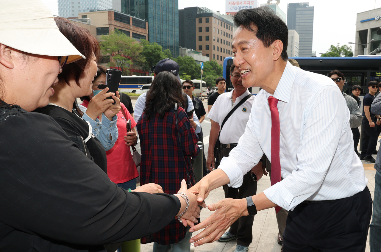 Seoul Mayor Oh Se-hoon shakes hands with members of the public in front of Seoul City Hall on Thursday. (Yonhap)
