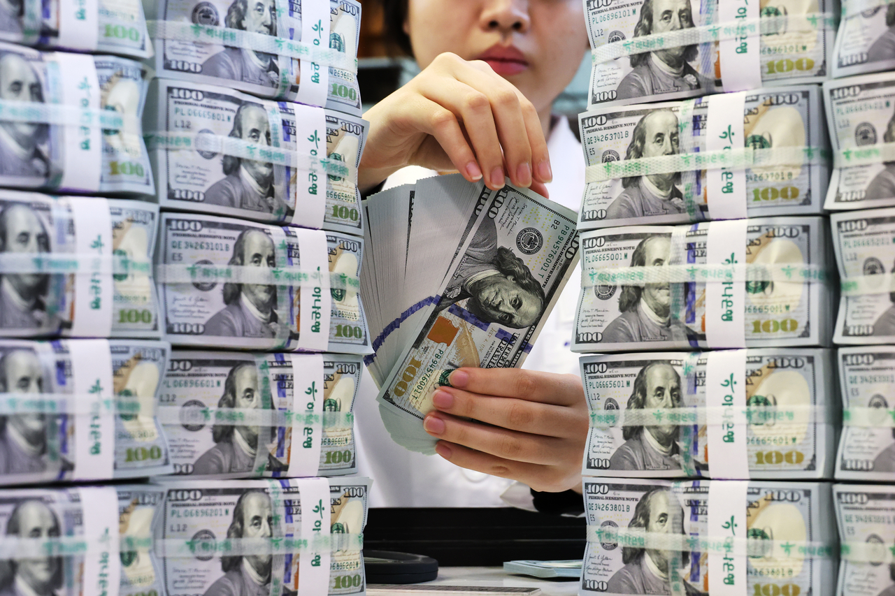 A staff member holds dollar bills at Hana Bank’s anti-counterfeiting center in Jung-gu, Seoul, on April 7. (Yonhap)