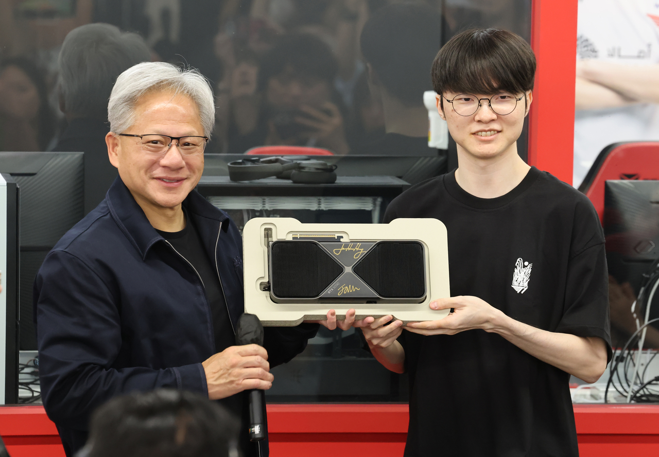 Jensen Huang (left), CEO of Nvidia, and Lee "Faker" Sang-hyeok pose with GeForce graphics cards autographed by both at T1 Base Camp in Mapo-gu, Seoul, Friday afternoon. (Yoon Chang-bin/The Korea Herald)