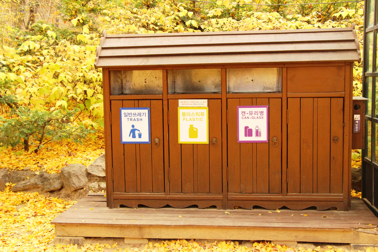 A photo of a vintage wooden waste bin, with separated sections each for general waste, plastic and cans and glass (123rf)