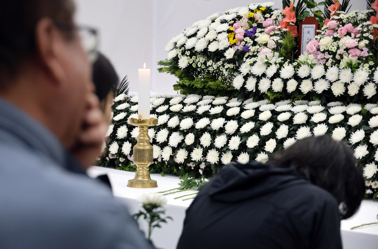 Bereaved family members of the victims of the explosion at Hanwha Aerospace's Daejeon facility mourn before the portraits of their loved ones at a joint memorial altar set up at the Yuseong District Office in Daejeon on Friday. (Yonhap)
