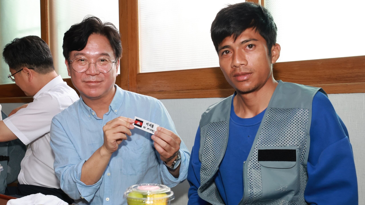Kim Young-hoon (left) presents a name tag to a Cambodian worker at a farm in Wanju, North Jeolla Province, as part of a campaign encouraging employers to address international workers by their names. (Ministry of Employment and Labor)