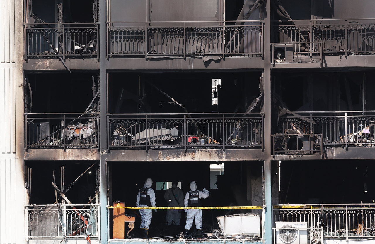 Police, fire department officials and National Forensic Service investigators examine the scene of an apartment fire in Uiwang, Gyeonggi Province, on May 1 to determine the cause of the blaze. [Yonhap]