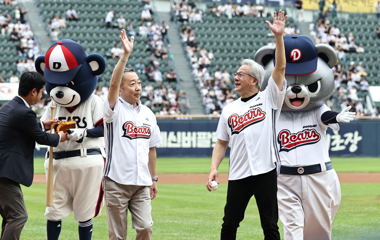Nvidia CEO Jensen Huang leaves the field with Doosan Group Chairman Park Jeong-won after throwing the ceremonial first pitch before a KBO League game between the Kiwoom Heroes and the Doosan Bears at Jamsil Baseball Stadium in Seoul on Sunday. Park served as the ceremonial batter. (Yonhap)