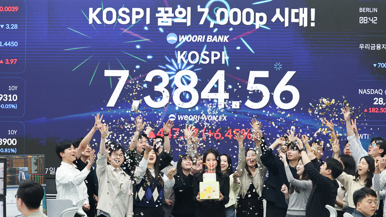 Woori Bank traders celebrate after the Kospi closed at 7,384.56, its first finish above the 7,000 mark, at a dealing room in Seoul on Wednesday. (Yonhap)