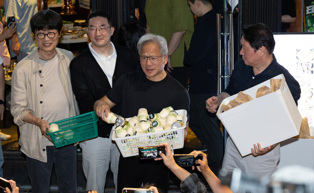 From left: Naver Chair Lee Hae-jin, LG Group Chair Koo Kwang-mo, Nvidia CEO Jensen Huang and SK Group Chair Chey Tae-won hand out snacks to the public gathered outside a pork belly restaurant in Hongdae, Seoul, on Friday. (Yoon Chang-bin/The Korea Herald)