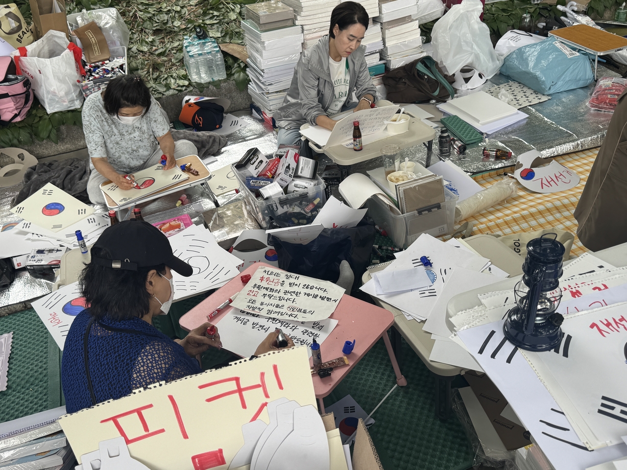 Volunteers make picket signs for a gathering calling for a rerun of the recent local elections in Jamsil-dong, southern Seoul, Sunday. (Cha Min-jung/The Korea Herald)