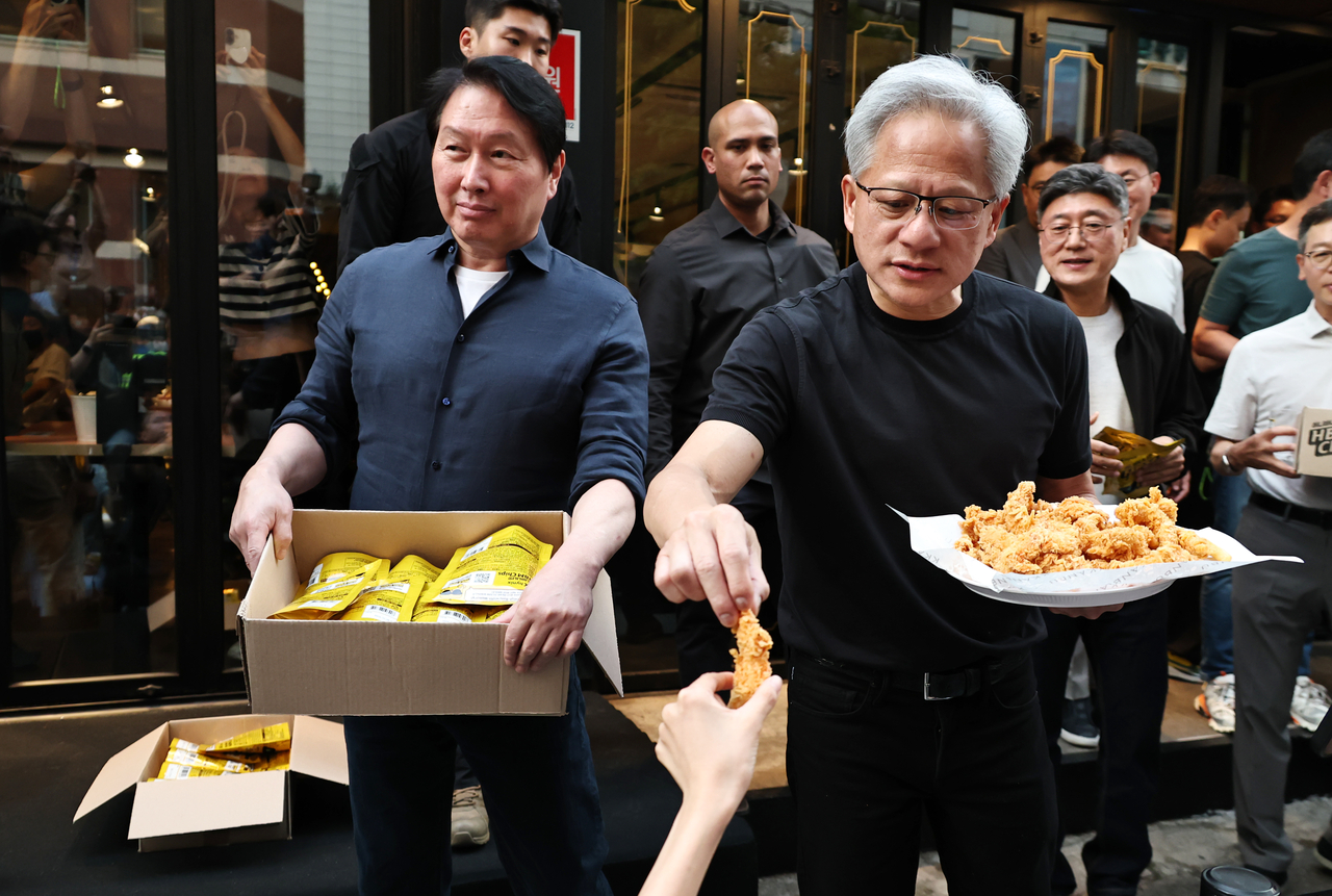 Nvidia CEO Jensen Huang (right) and SK Group Chairman Chey Tae-won share HBM chips and fried chicken with people during their chicken-and-beer gathering at Kkanbu Chicken in southern Seoul, on Sunday. (Yonhap)