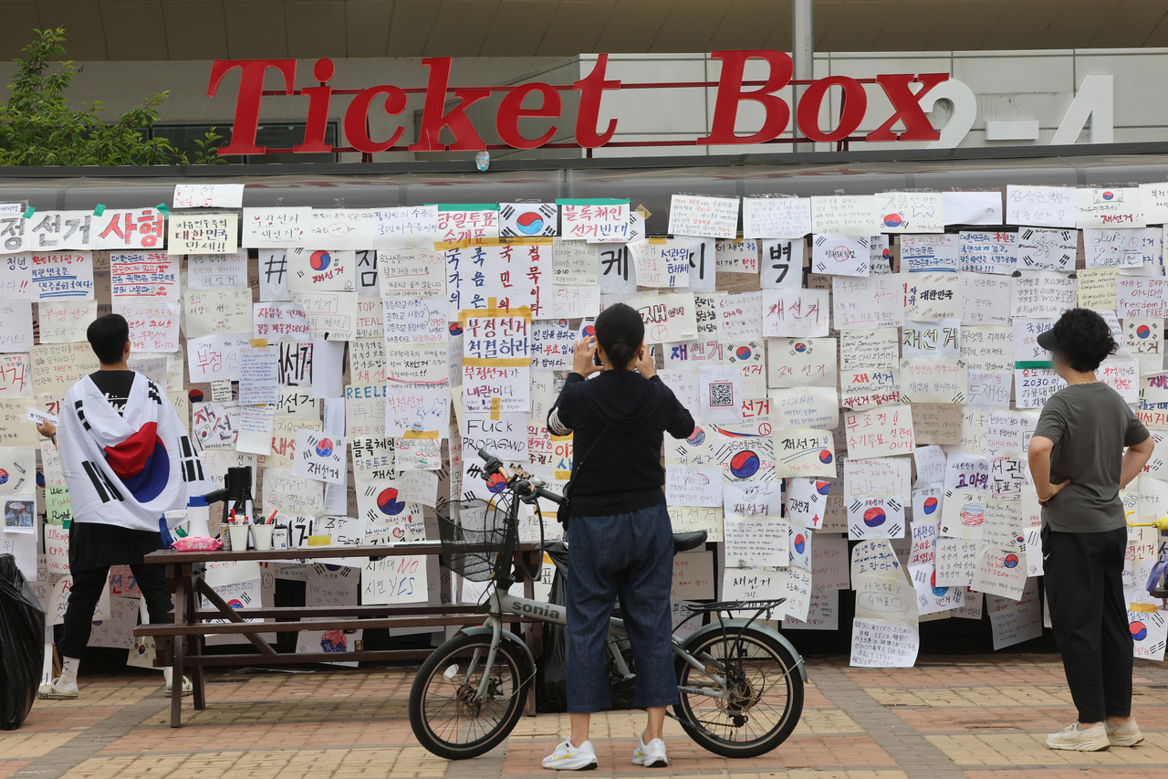 Paper slips with a message calling for a new election are attached on a ticket box as protesters continue to stage a rally in front of the SK Olympic Handball Gymnasium, used as a vote-counting facility, in Seoul's Songpa Ward on Monday, over an unprecedented shortage of ballot papers that disrupted voting in the June 3 local elections at some polling stations in the capital's southern areas. (Yonhap)