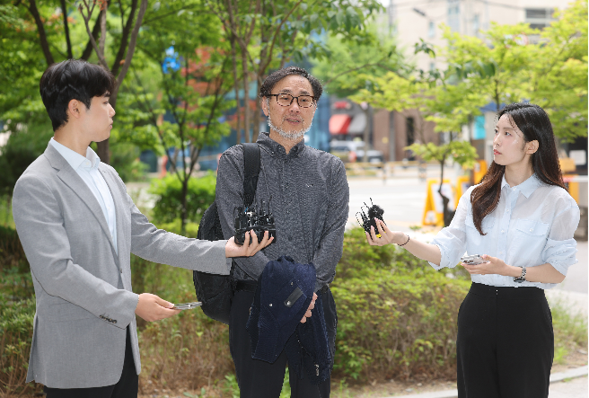 Civic group People's Welfare Countermeasure Committee Secretary-General Kim Soon-hwan (center) speaks to reporters Monday as he arrives at the Seoul Gangdong Police Station for questioning after the group filed a complaint against NEC Chair Rho Tae-ak . (Yonhap)