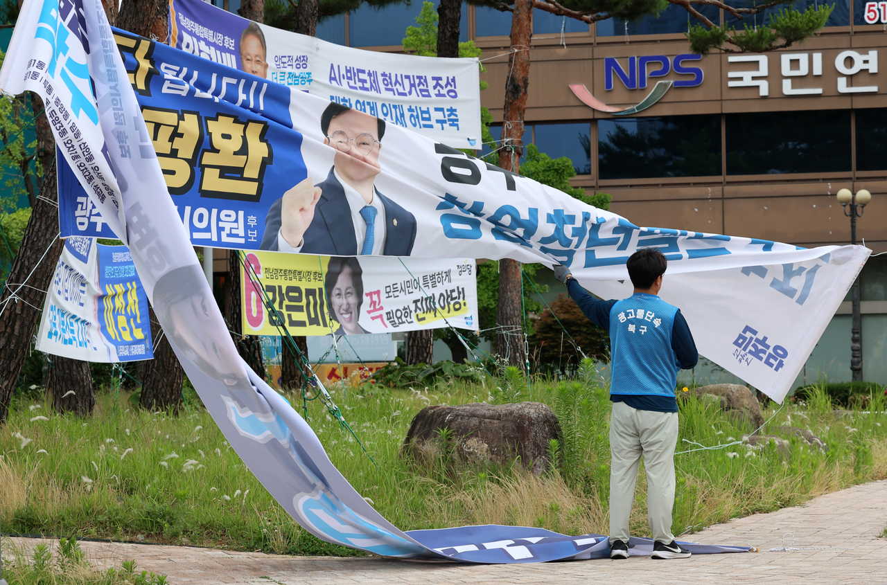 A worker removes campaign banners from the ninth nationwide local elections outside Gwangju Station on Thursday. (Yonhap)