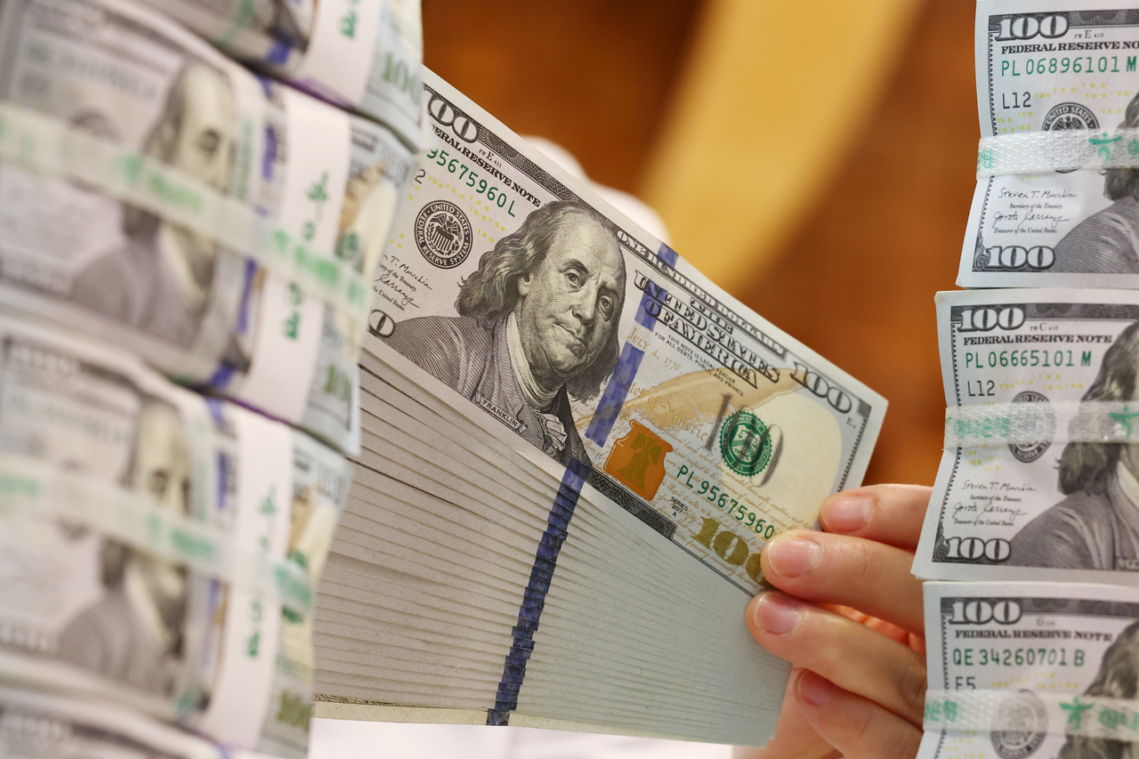 A Hana Bank employee holds up US dollar bills at the bank's headquarters in central Seoul on Thursday. (Yonhap)