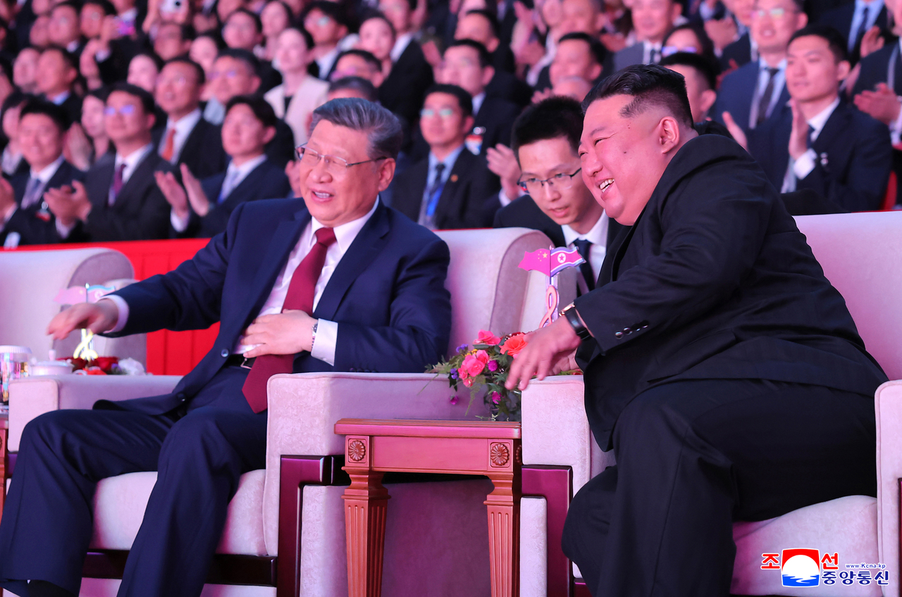 Chinese President Xi Jinping (left) and North Korean leader Kim Jong-un attend a performance at the Pyongyang Indoor Stadium held Monday to welcome Xi during his state visit to North Korea, according to the Korean Central News Agency on Tuesday. (Yonhap)