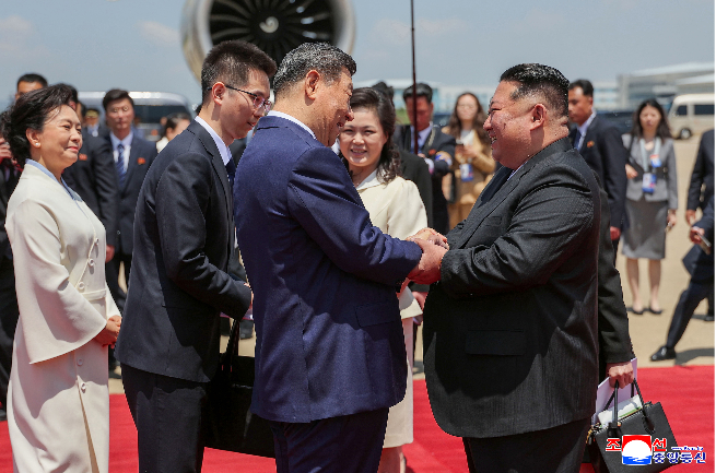 North Korean leader Kim Jong-un (right) welcomes Chinese President Xi Jinping  at Pyongyang Sunan International Airport on Monday in this Korean Central News Agency photo released the next day. (KCNA via Yonhap)