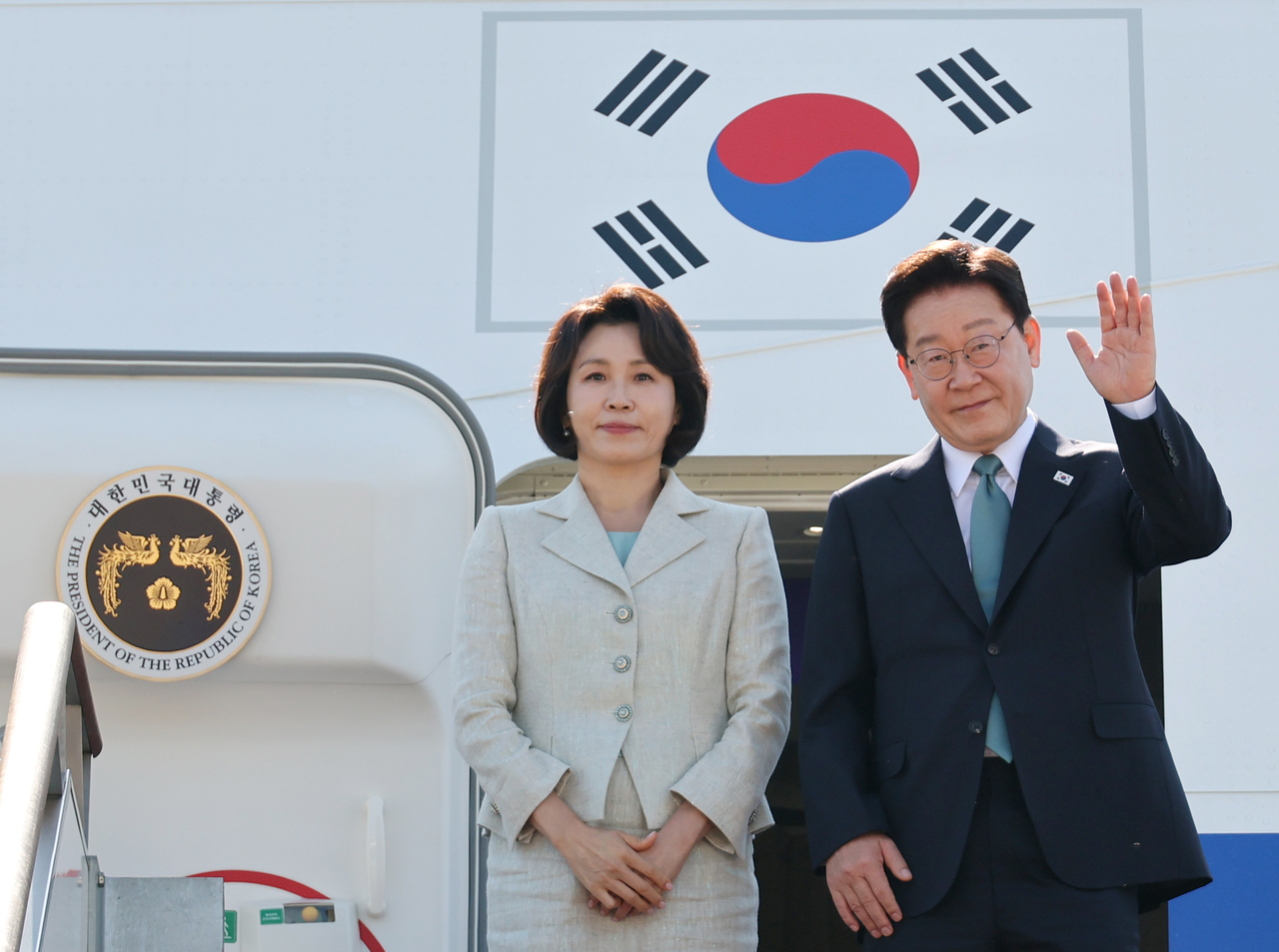 President Lee Jae Myung (R) and first lady Kim Hea Kyung board the presidential plane at Seoul Air Base, south of the capital, on Tuesday, to depart for a trip to Europe. (Yonhap)