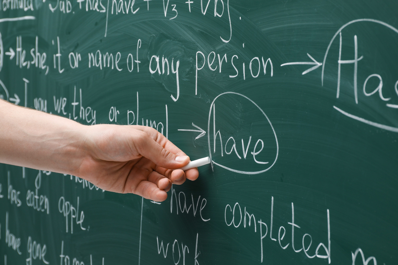 A teacher writing on chalkboard. (123rf)