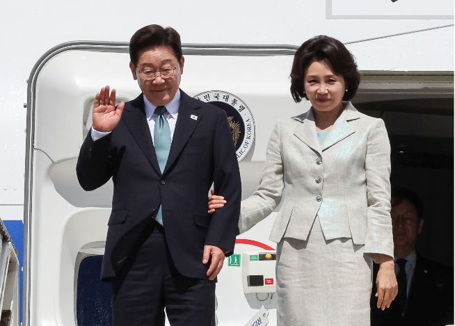 President Lee Jae Myung (left) waves to Belgian officials and others in the welcoming party after arriving aboard the presidential aircraft at Melsbroek Air Base in Brussels on Tuesday. (Yonhap)