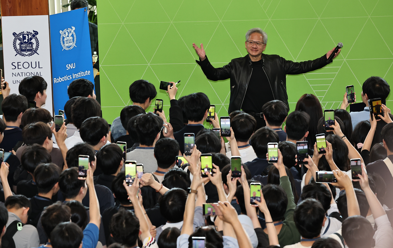 Nvidia CEO Jensen Huang smiles as Seoul National University students film him during Monday’s Build-a-Claw event at the Haedong Advanced Engineering Building, where his joke that Korea should call him “K-Jensen” drew cheers from the crowd. (Lee Sang-sub/The Korea Herald)