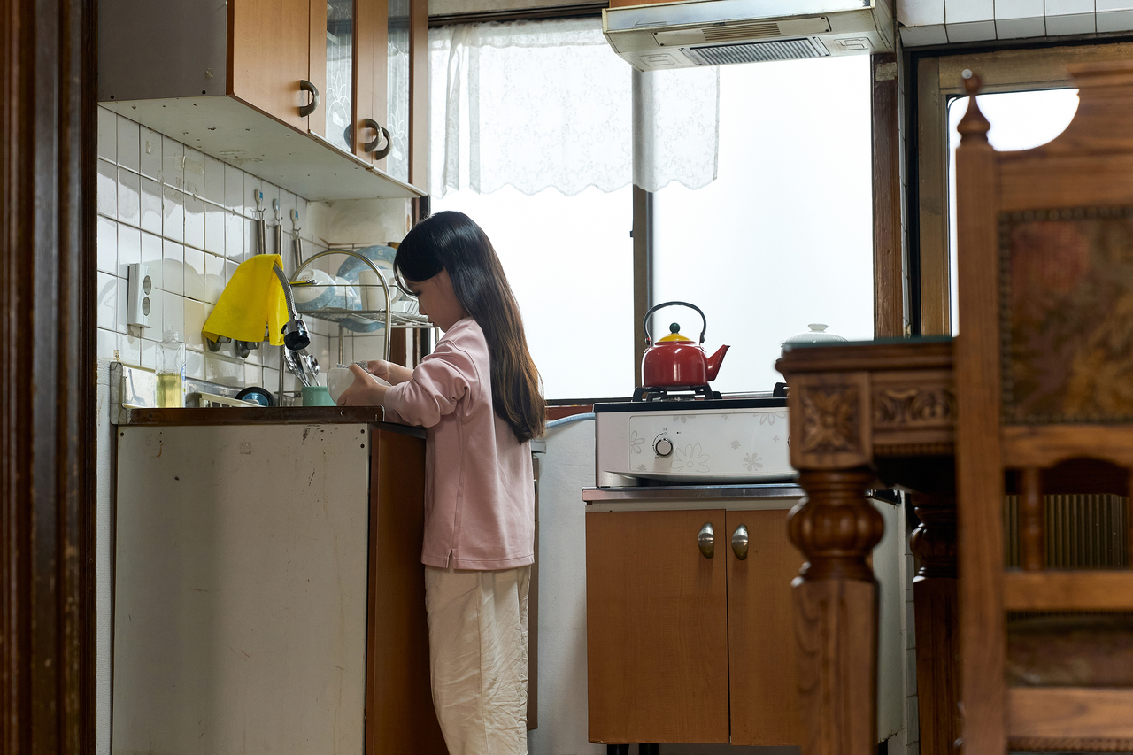 A young girl washes dishes by herself. (Getty Image)