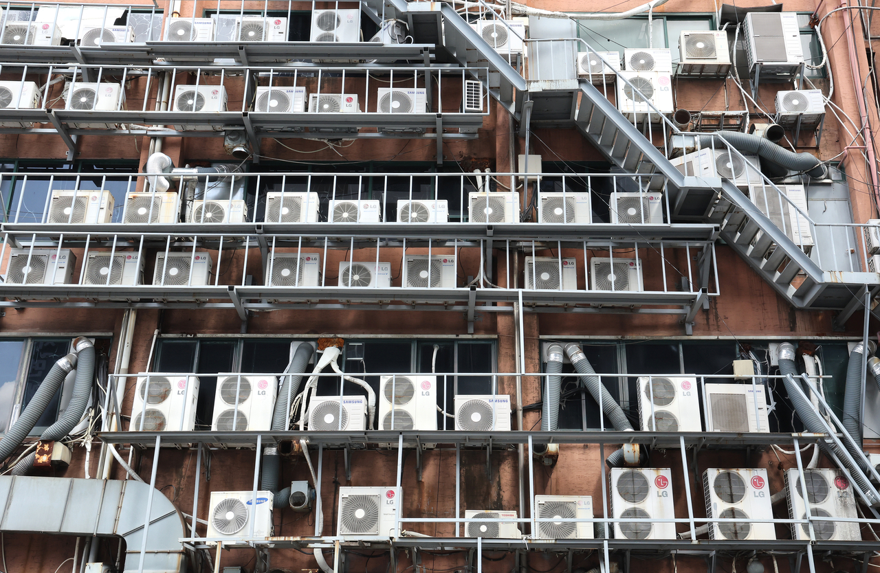 Outdoor air-conditioning units are mounted outside an apartment building in Busan. Such installations were common in older apartment buildings constructed before regulations were revised in 2006 to require designated balcony space for outdoor units. (Yonhap)