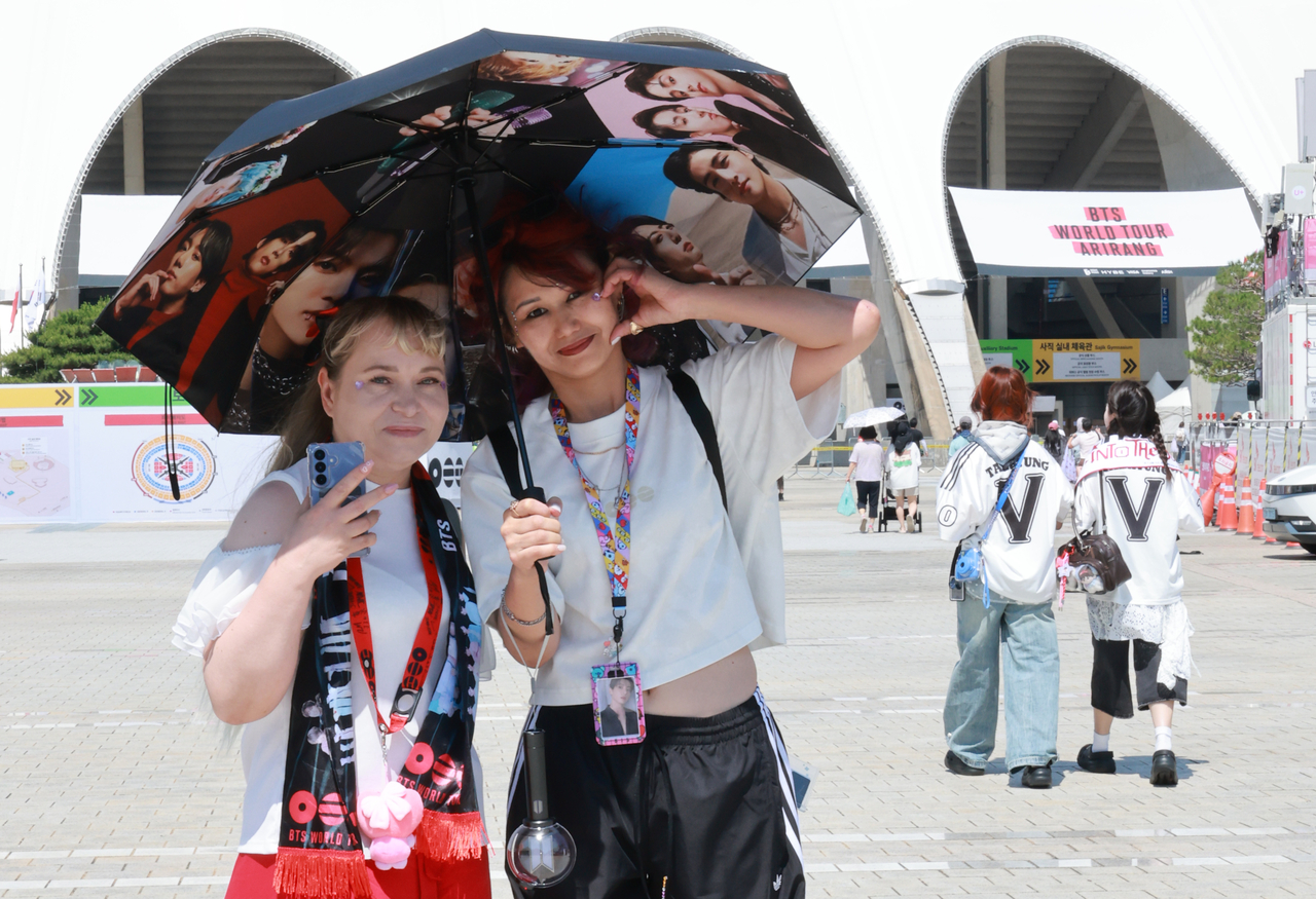Fans holding a parasol decorated with photos of BTS members stand outside Busan Asiad Main Stadium in Busan on Friday. (Yonhap)