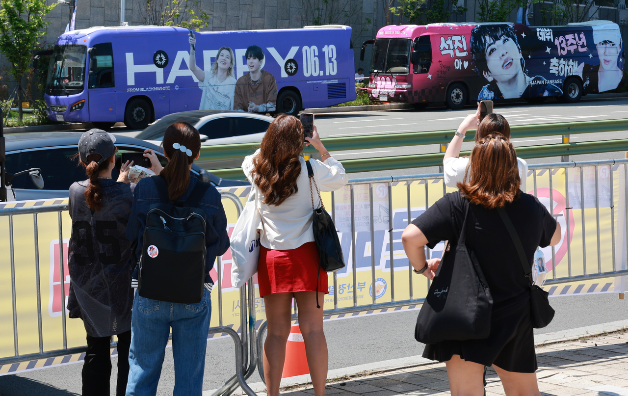 Fans photograph buses wrapped with images of BTS members outside Busan Asiad Main Stadium in Busan on Friday, where the group's concert is set to take place later in the evening. (Yonhap)