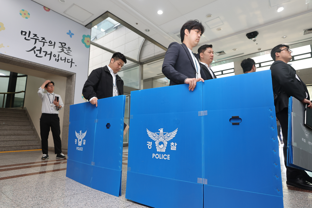 Police officials enter the National Election Commission headquarters in Gwacheon, Gyeonggi Province, on Thursday to conduct a search and seizure operation related to ballot paper shortages during the June 3 local elections. (Yonhap)