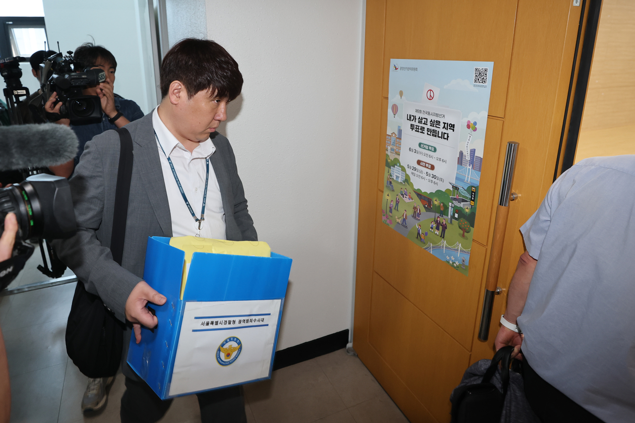 A police official carries out evidence from the National Election Commission headquarters in Gwacheon, Gyeonggi Province, during its raid on Thursday. (Yonhap)