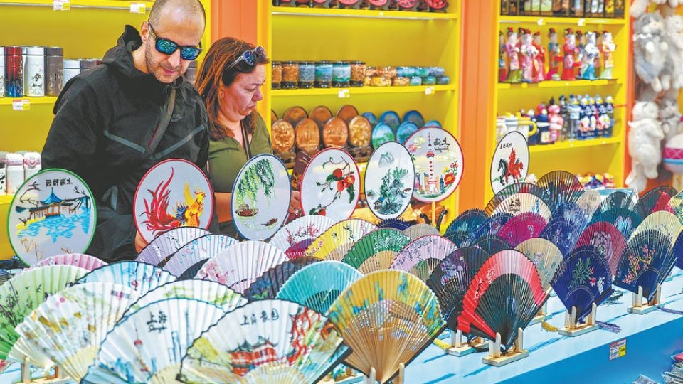 Foreign tourists shop for folding fans and other traditional Chinese souvenirs in Shanghai.   (China Daily)