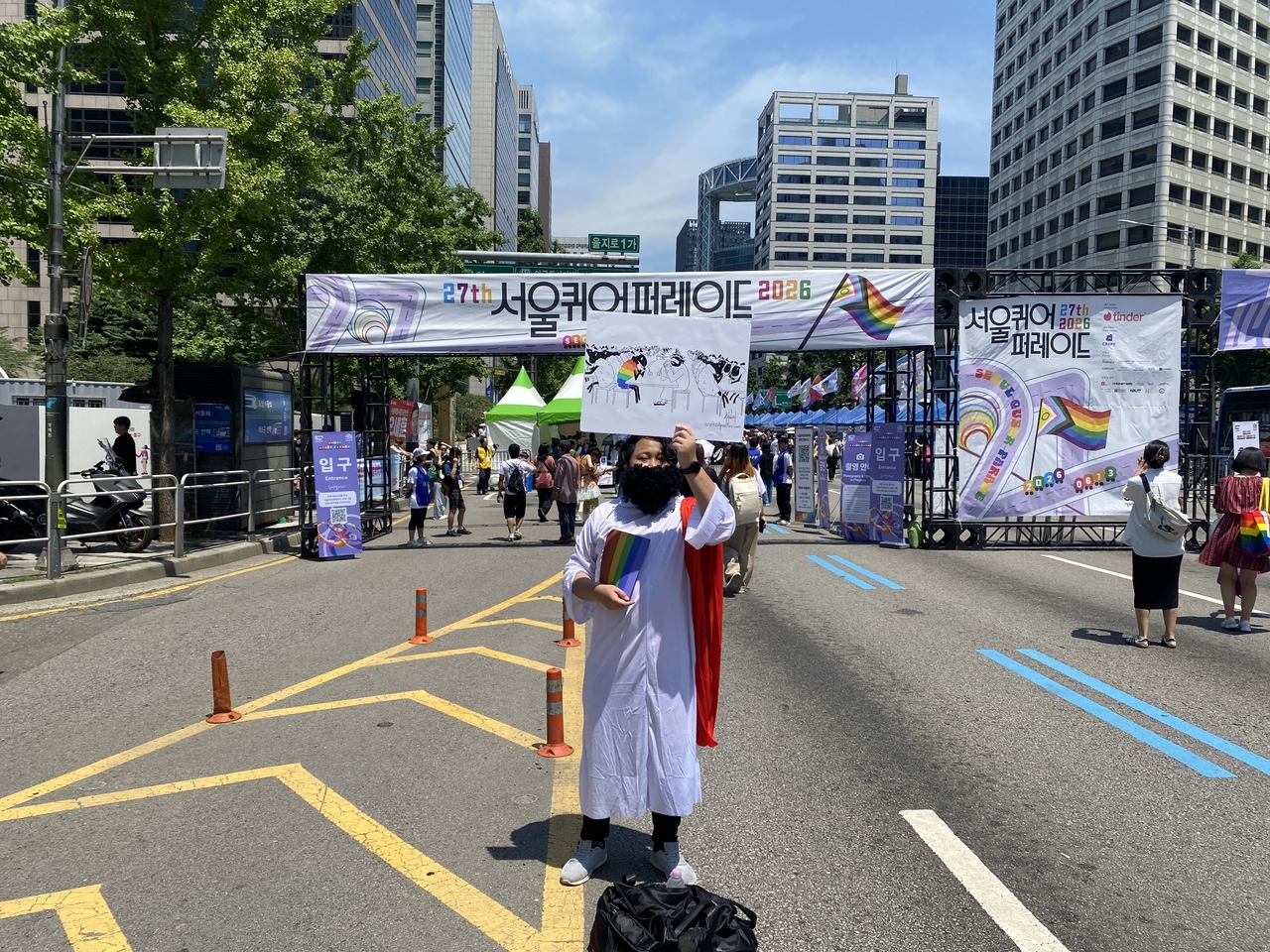 A demonstrator identifying himself only as "B" poses in a Jesus costume outside the main entrance to the 2026 Seoul Queer Parade in central Seoul on Saturday, expressing his support. (Lim Jae-seong/The Korea Herald)