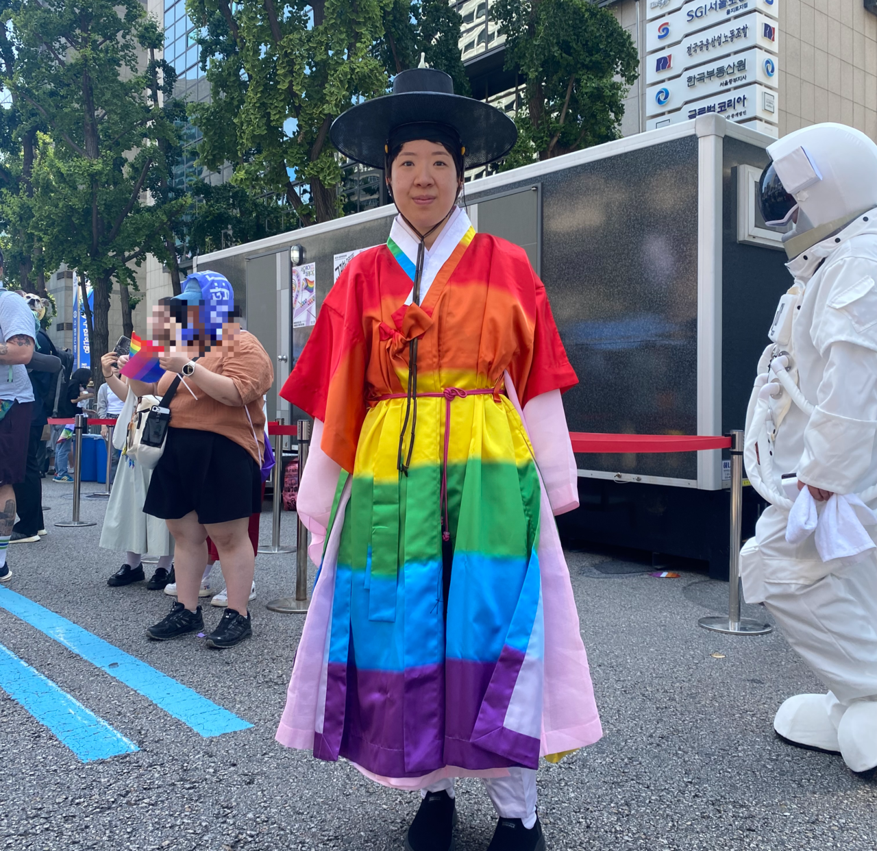 Kim Min-ji, 34, poses after an interview with The Korea Herald during the 2026 Seoul Queer Parade in central Seoul on Saturday, wearing a rainbow-colored dopo and gat, traditional Korean attire worn by noblemen. (Lim Jae-seong/The Korea Herald)